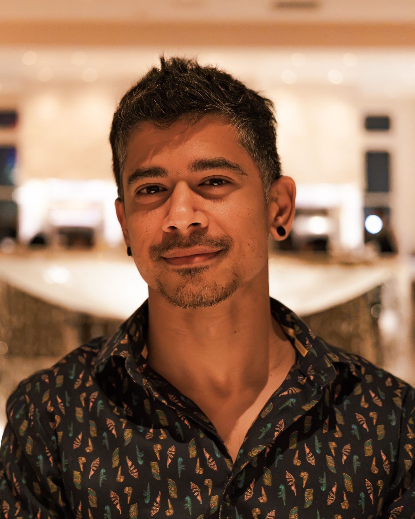 Sundar smiling in a dark patterned shirt, in a softly lit hotel lobby at night